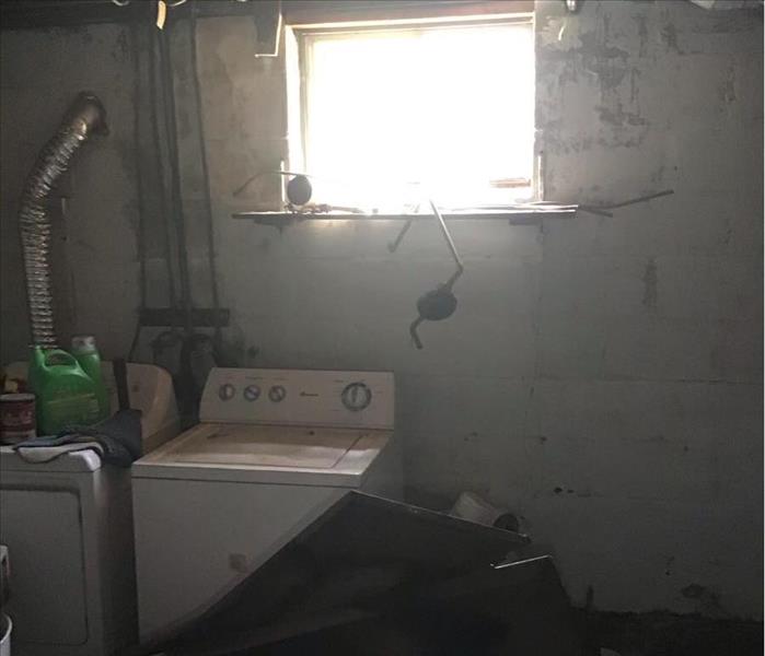 A dark laundry room/basement with a large debris in front of it. 