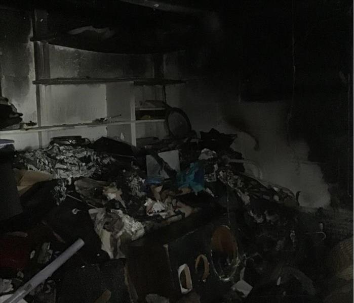 A dark basement cluttered with content and rubble on the floor after a fire.