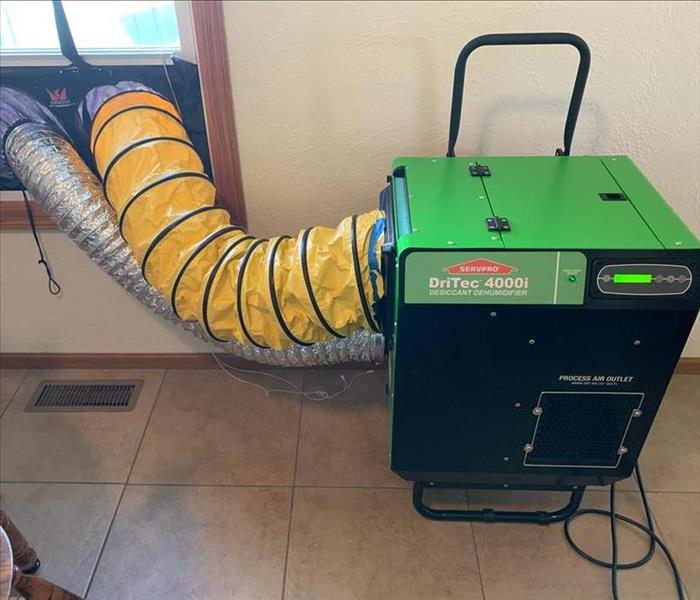 A green equipment with 2 hoses going outside from a nearby window.