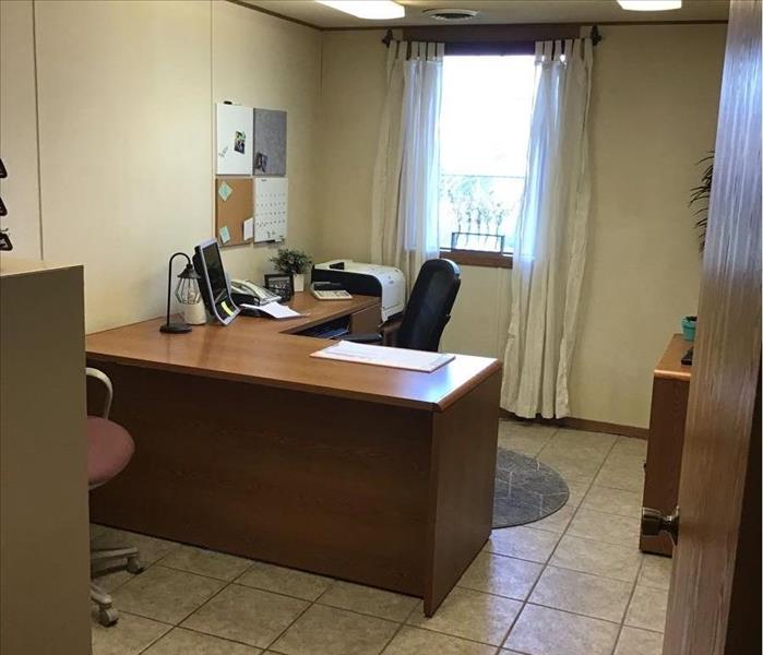 An office with one window and an empty desk. 