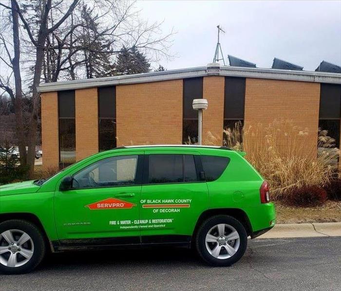 Green servpro car in front of brown brick building