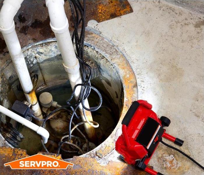 Picture of sump pump battery backup in basement with SERVPRO logo